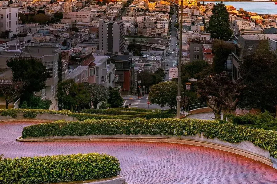 Die Lombard Street schlängelt sich bei sunset durch die Ferne mit Coit Tower .